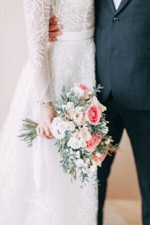 Floristry of eucalyptus and Ranunculus in the hands. The bride's bouquet in the bright Studio. 