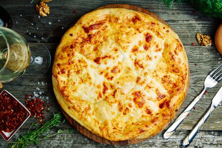 Azerbaijani restaurant dish with vegetable decor on a wooden background. Khachapuri in Megrelian on the Board.の写真素材