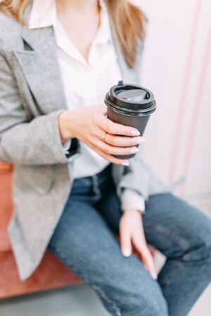 Girl blogger with coffee sitting in a coffee shop and working. Laptop and phone in hand. Business style in clothes.の写真素材