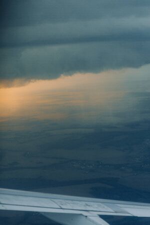 View from the plane at altitude, flying over the clouds. Sunset in the sky, a journey from the...