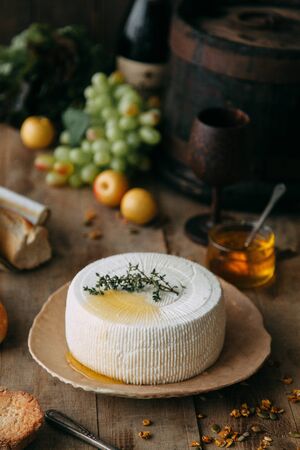  A large white round cheese on a plate. Curd cheese is watered with honey. The chef's hands prepare cheese.の写真素材