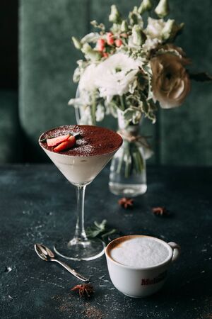 Tiramisu and fried pancakes on a plate. Tiramisu dessert in a cocktail glass in the restaurant.の写真素材