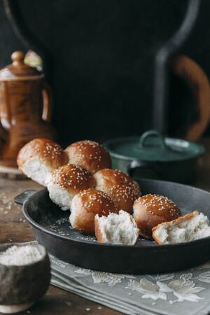 Buns and bread baking on dark wooden background. Food styling and cooking with fresh ingredients.