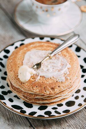 pancakes with butter and sour cream on light wooden background composition with flowers and teaの写真素材