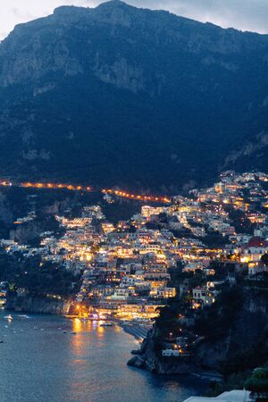 The coast of Positano, Amalfi in Italy. Panorama of the evening city and the streets with shops and cafes. Houses by the sea and the beach. Ancient architecture and temples. View from a postcard on topの写真素材