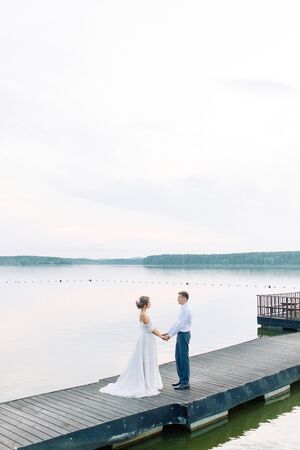Stylish European wedding at sunset. Happy couple on the pier on the lake. の写真素材