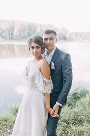 Stylish European wedding at sunset. Happy couple in the forest on the lake.の写真素材