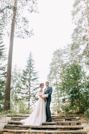 Modern ceremony in European style. Beautiful wedding couple in atmospheric forest with rocks.の写真素材