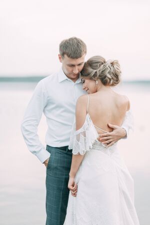 Stylish European wedding at sunset. Happy couple on the pier on the lake.の写真素材