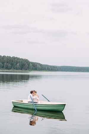 Stylish wedding in European style. Happy couple on a boat on the lake.の写真素材