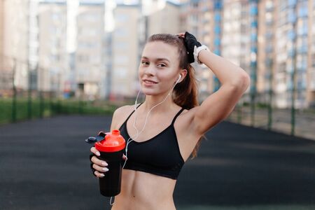 sporting a young girl in the gym and the stadium, warming up before exercise and listening to music