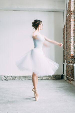 A young ballerina is getting ready, stretched and dancing. Poses in ballet. Photo shoot in the loft Studio. Russian Ballerina at the bench. ballet flats and dance dressの写真素材