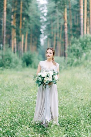 Boudoir photo shoot of the bride in the woods with a bouquet. Flying dress and beautiful girl in the Park.の写真素材