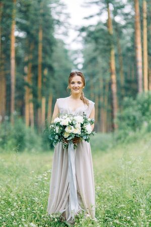 Boudoir photo shoot of the bride in the woods with a bouquet. Flying dress and beautiful girl in the Park.の写真素材