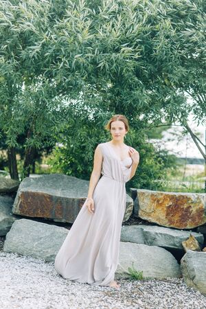 Boudoir photo shoot of the bride in the Park with a bouquet. A flying dress and a beautiful girl by the lake.の写真素材