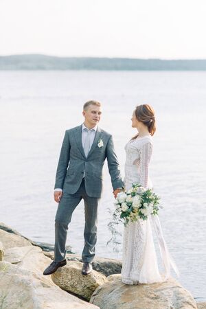 A young couple of newlyweds on the pier by the water. Wedding photo shoot at sunset.の写真素材