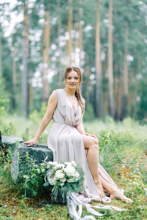 Boudoir photo shoot of the bride in the woods with a bouquet. Flying dress and beautiful girl in the Park.の写真素材