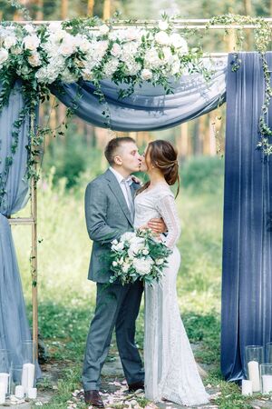 Wedding ceremony at the arch with pine forest in the style of fine art. Beautiful couple and traditions at a wedding in Europe.の写真素材