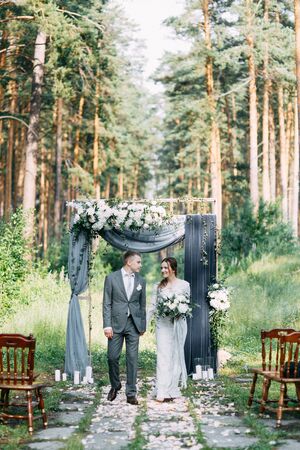 Wedding ceremony at the arch with pine forest in the style of fine art. Beautiful couple and traditions at a wedding in Europe.の写真素材