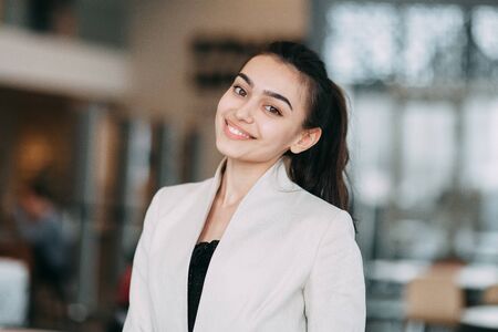 Beautiful Russian business girl standing with arms crossed and smiling. Office style and business image, business meeting and greetingの写真素材
