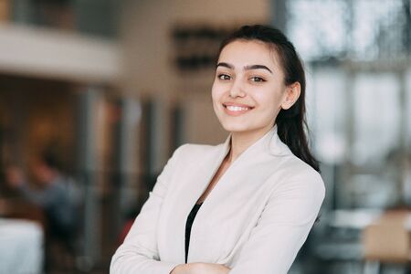 Beautiful Russian business girl standing with arms crossed and smiling. Office style and business image, business meeting and greetingの写真素材