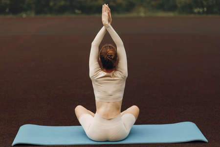 Athletic girl on the Mat is warming up. Training at the stadium with stretching.の写真素材