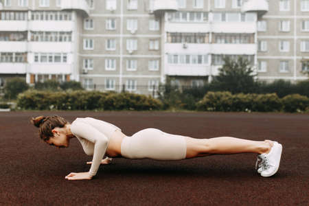 A sporty woman trains and exercises at a fitness stadium. Warm-up in the open air, stretching.の写真素材
