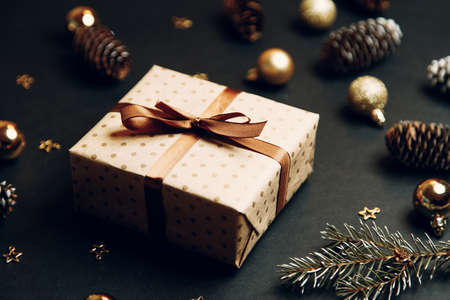 Christmas composition with a gift in a box. Golden toys, modern holiday decorations, gift boxes, fir...