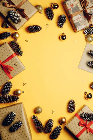 Christmas composition. Christmas gift, Christmas toys, pine cones, fir branches on a yellow background. Flatlay, top view, copy space.の写真素材