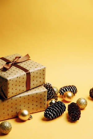 Christmas composition, copy space. Christmas gift, Christmas toys, pine cones, fir branches on a yellow background.の写真素材