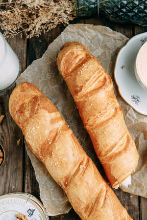 Bread lying on a dark wooden background. Top view of fresh wholegrain bread with butter on paper.の写真素材
