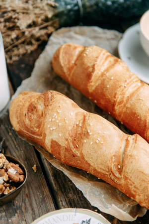 Bread lying on a dark wooden background. Top view of fresh wholegrain bread with butter on paper.の写真素材