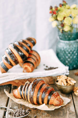 Composition of desserts on a wooden table. Chocolate croissants in caramel glaze close-up.の写真素材