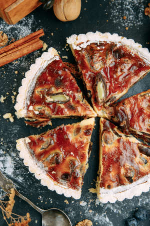 Fruit cake cut into slices close-up on a dark table. Date cake with sweet jam and shortbread.