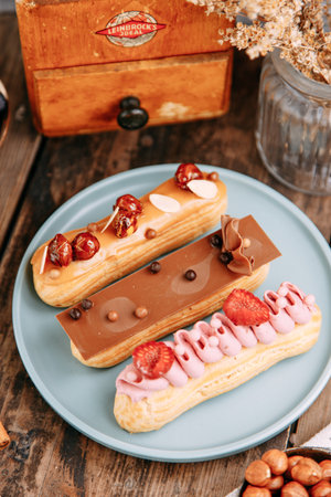 Eclairs decorated with chocolate and berries on a plate. Traditional French eclairs with cream.