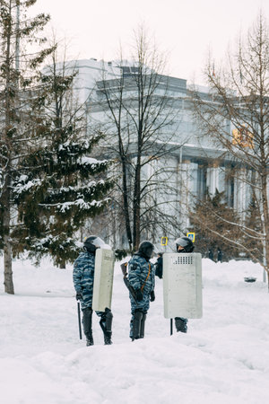 Yekaterinburg, Russia - January 23, 2021: Riot police run to disperse civilians. Military with weapons and shields in winter.のeditorial素材