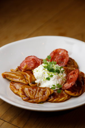 Restaurant serving dishes close-up. Traditional steamed dumplings with tomato sauce and sour cream.