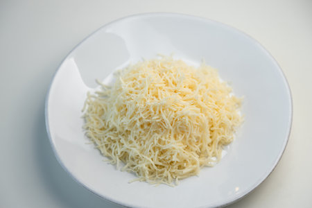 Grated cheese salad, restaurant serving of the dish. Grated cheese on a white plate close-up.の写真素材