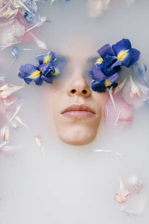 A sensual portrait of a woman in a bath with milk and flowers. Spa treatments, soft skin and soft...