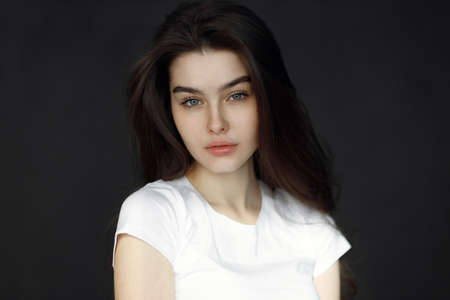 Close-up portrait of a young beautiful woman, on a dark background. Beauty portrait of a girl, studio tests.の写真素材