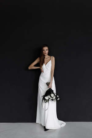 A modern trendy bride in an elegant dress. Beautiful woman in a white wedding dress on a black background.の写真素材