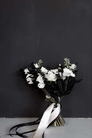 Modern trends in the decor of a wedding bouquet with colored flowers. Stylish black bridal bouquet on a dark background.の写真素材