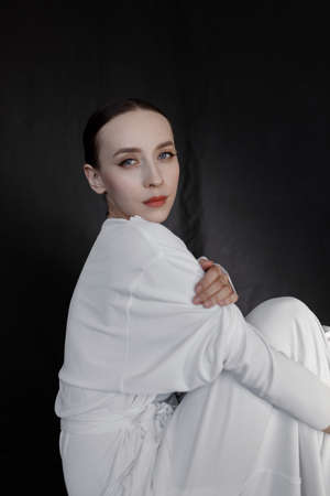 Portrait of a beautiful girl isolated on a dark background. A pale girl in a white dress, the style of a modern geisha.の写真素材