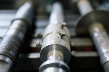 Old iron shafts on a lathe. Rusty shafts close-up, shiny metal with a blurred background.の写真素材