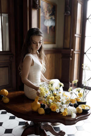 A trendy image of the bride in a dark interior, laconic European style. A stylish modern bride in a white dress with a cutout, a conceptual image.の写真素材