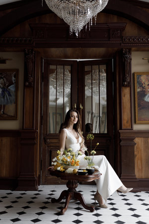 A trendy image of the bride in a dark interior, laconic European style. A stylish modern bride in a white dress with a cutout, a conceptual image.の写真素材