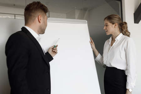 A couple of men and women stand at the flipchart and discuss business issues. Portrait of a couple...