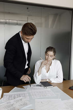 A man and a woman discuss business matters. A couple working at a laptop and blueprints in their home office smile.の写真素材