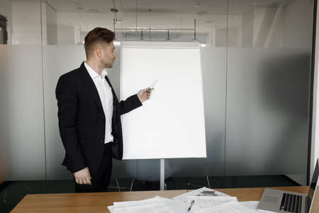 The man stands at the flipchart and smiles. A successful businessman with a flipchart in his...