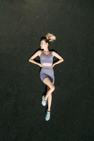 Warm-up in the open air, stretching. A sporty woman trains and exercises at a fitness stadium.の写真素材
